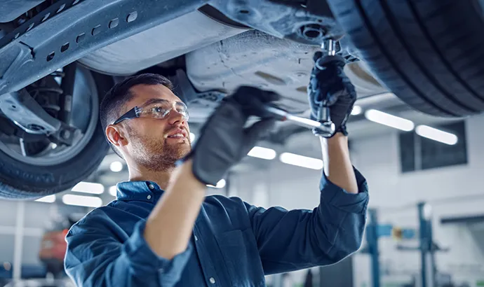 Mechaniker am Fahrzeug in einer modernen Werkstatt, unterstützt durch ein Headless CMS mit React